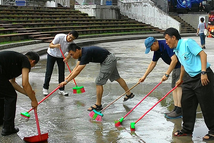 為了讓觀眾有最好的體驗，一群夢蓮花讚頌團的男性團員，趁著彩排的空檔，整理因颱風來襲、大雨積水的演出場地。